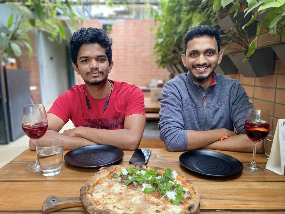 Two Creo teammates sharing pizza and a glass of wine